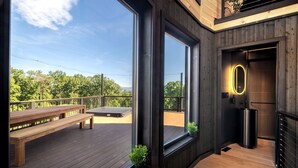 Een modern interieur met een houten terras, een bank, een potplant en een badkamer met een spiegel.