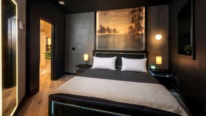 Een moderne slaapkamer met een groot bed, twee nachtkastjes, een hoofdbord en een groot schilderij aan de muur.