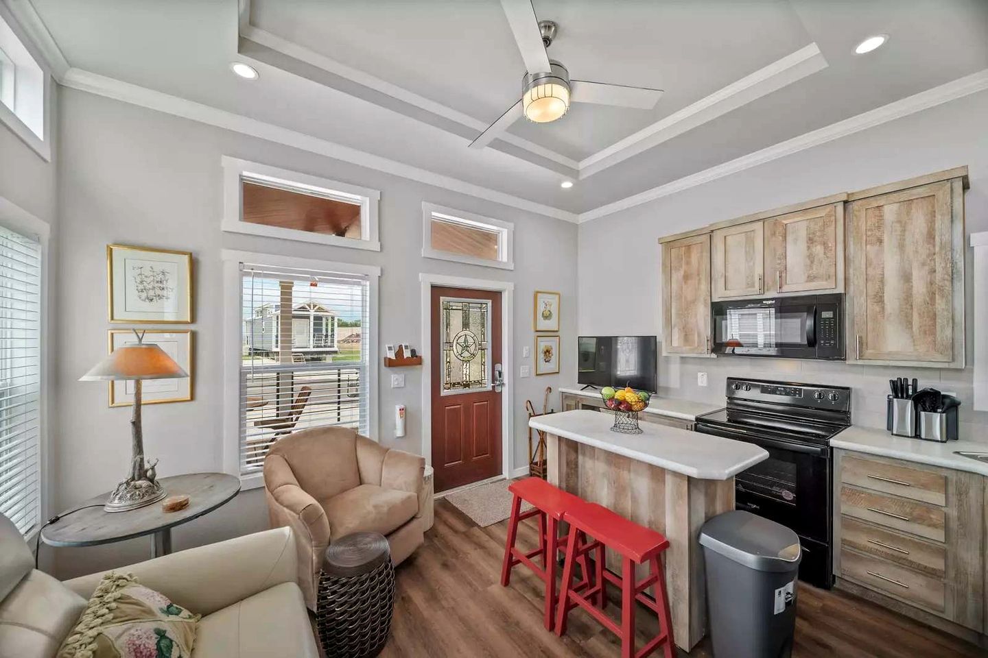 A modern kitchen with a central island, wooden cabinets, and a built-in microwave.