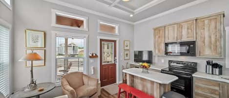 A modern kitchen with a central island, wooden cabinets, and a built-in microwave.