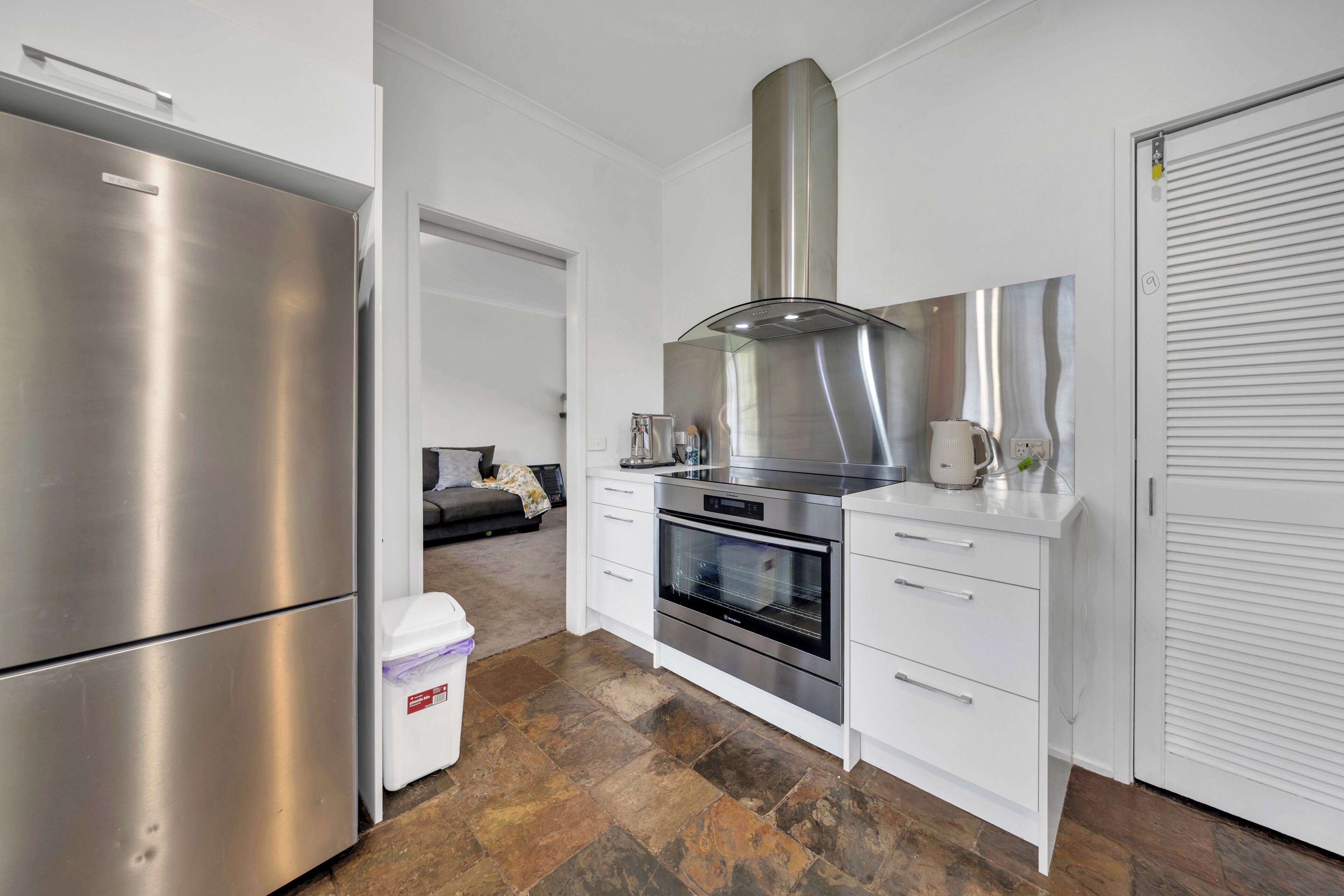 A modern kitchen with stainless steel appliances, a built-in oven, and white cabinetry.