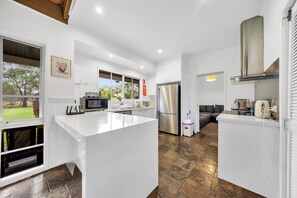 A modern kitchen with white cabinetry, a stainless steel refrigerator, and a large island.