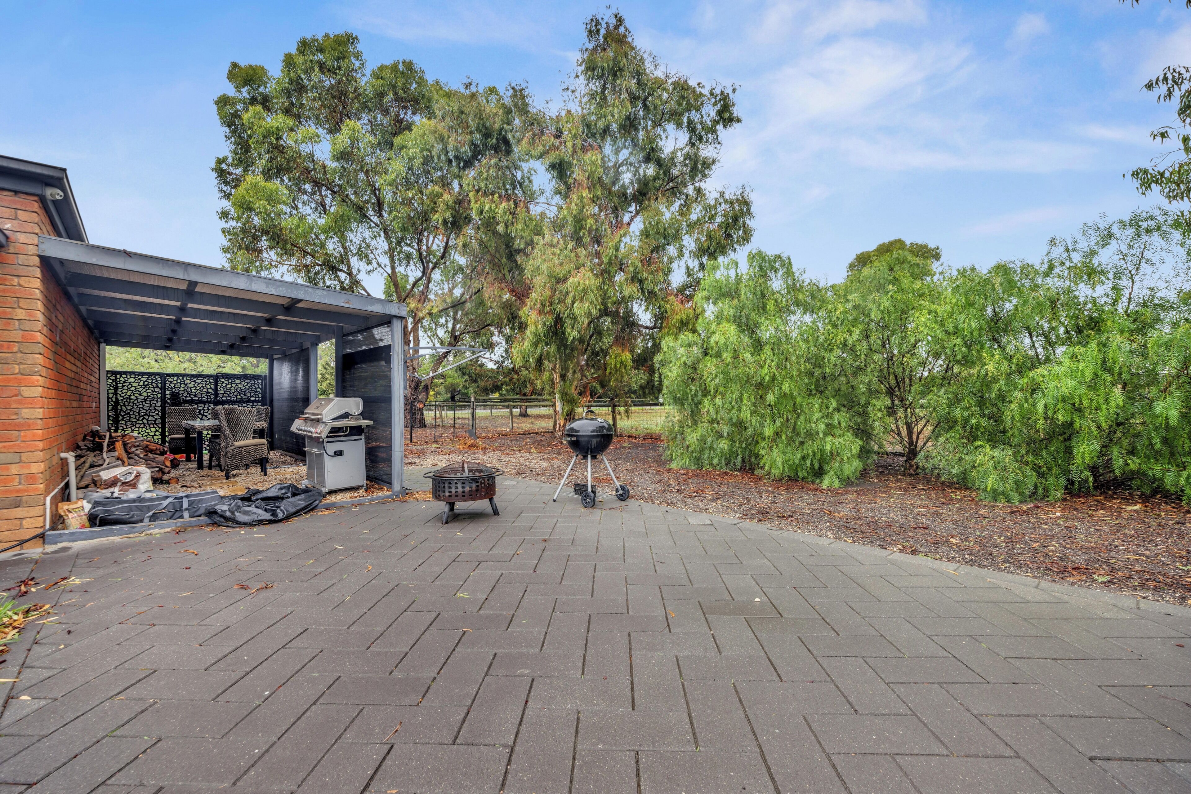 A patio area with a barbecue grill, a covered seating area, and a brick wall.