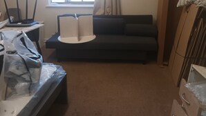 A room with a sofa, a small table, a window with curtains, and a desk with a computer. - Beautiful 2-bedroom apartment in London perfect for your stay (London)
