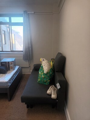 A small room with a black sofa, a green bag, and a pair of sneakers. - Beautiful 2-bedroom apartment in London perfect for your stay (London)