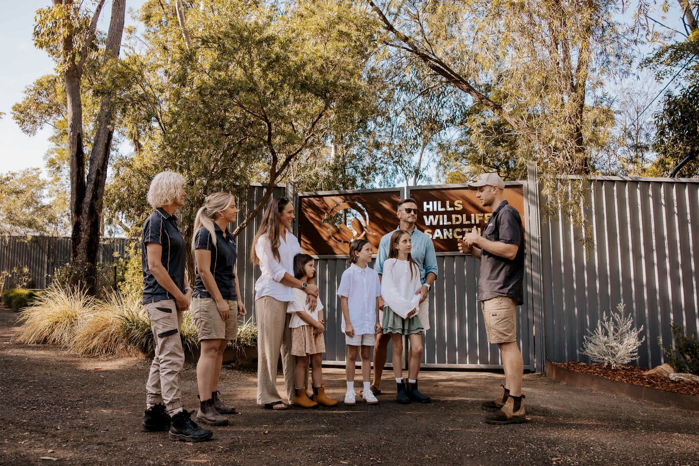 A group of people standing in front of a sign that reads 'HILLS WILDLIFE SANCTUARY.'