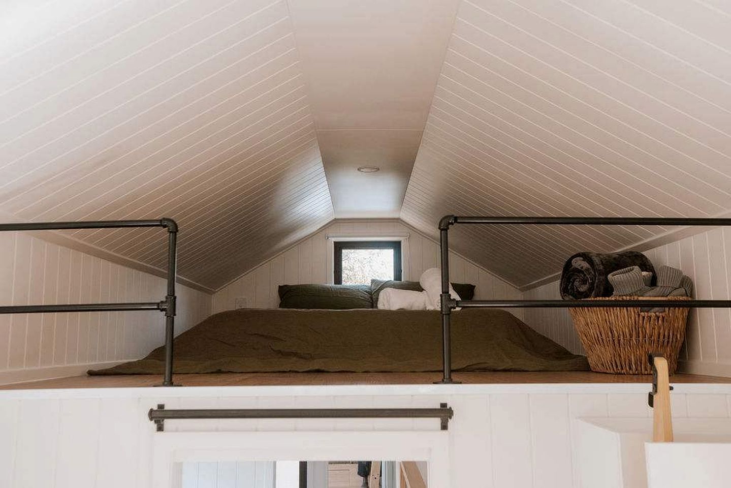 A dormitory-style room with bunk beds, a window, and a woven basket on the right side.