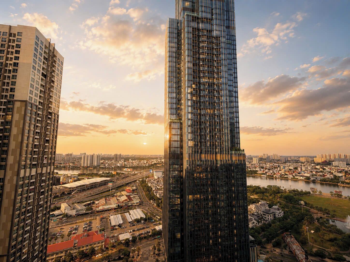 A high-rise building with a modern glass facade, surrounded by other tall buildings and a body of water.