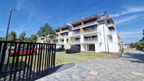 En flervåningsbyggnad med bostäder, balkonger, en asfalterad uppfart och parkerade bilar.
