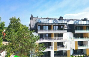 A modern multi-story building with balconies, large windows, and solar panels on the roof. - Posesja Plażowa Penthouse II & SPA (Grzybowo)