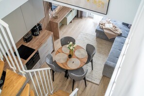 Une cuisine moderne avec un coin repas, un escalier et un espace de vie comprenant un canapé et une couverture.