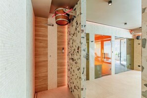A modern interior with a wooden wall, a textured floor, and a glass door leading to an outdoor area. - Posesja Plażowa Penthouse II & SPA (Grzybowo)