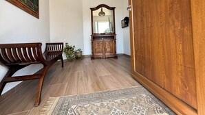A room with a wooden bench, a cabinet with a mirror, and a patterned rug on the floor.