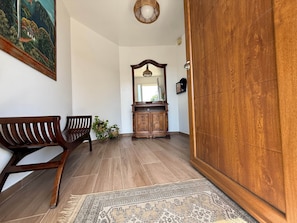 A room with a wooden bench, a cabinet with a mirror, and a patterned rug on the floor.