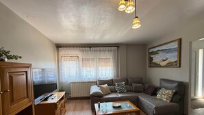 A living room with a sofa, a coffee table, a TV, and a painting on the wall.
