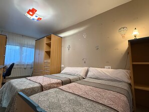 A bedroom with two beds, a desk, and a wardrobe.