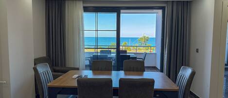 A hotel room with a balcony, a dining table, and chairs.