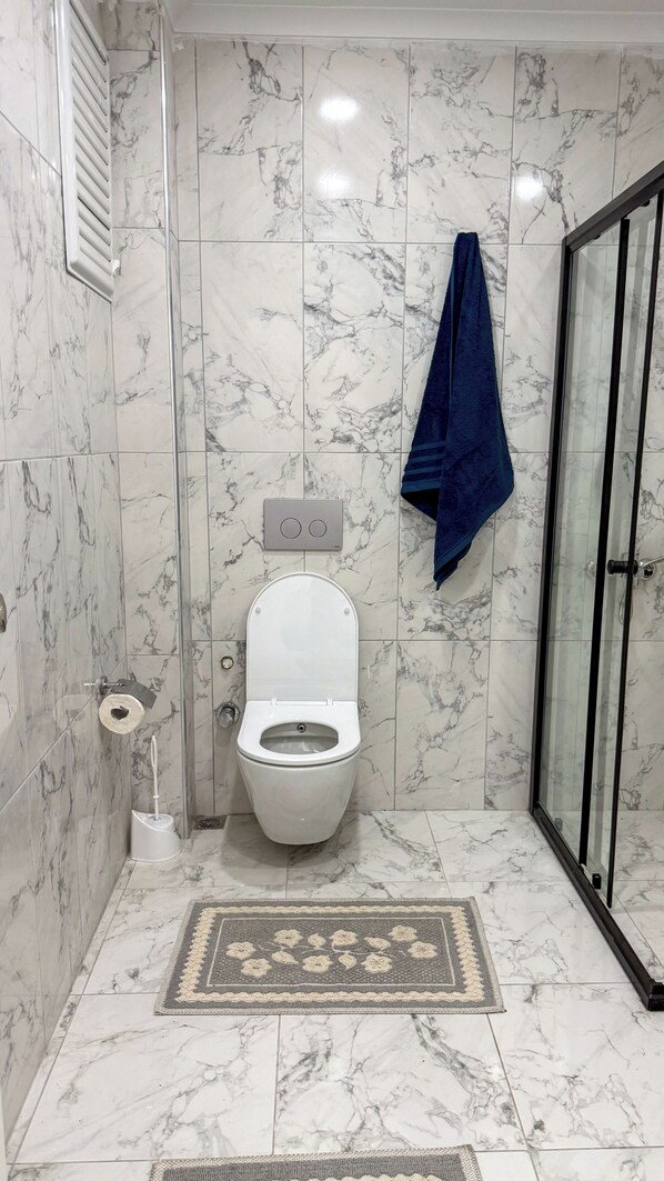 Une salle de bain avec des toilettes, une douche et une porte en verre.