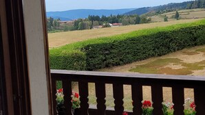 A view from a balcony with a railing, overlooking a landscape with fields and distant hills. - A peaceful mountain chalet at an elevation of 800 meters (Sapois)