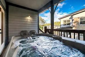 A hot tub on a porch with a view of neighboring houses. - Modern Cabin Retreat with Hot Tub & Game Loft in Pigeon Force, Tennessee (Pigeon Forge)