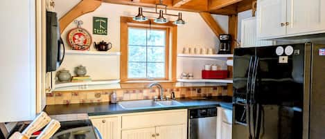 A kitchen with wooden beams, a black refrigerator, a sink, and a window.