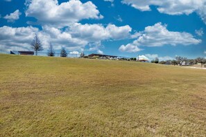 A grassy field with a clear sky and scattered clouds. - Scenic Hill Country Tiny Home with Pool & Community Amenities Near Fredericksburg, TX (Fredericksburg)