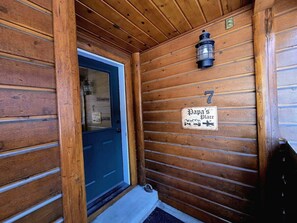 A wooden cabin entrance with a door, a sign reading 'Papa's Place,' and a lantern on the wall. - Charming Home with Golf Course Views & Relaxing Vibes in McCall, Idaho (McCall)