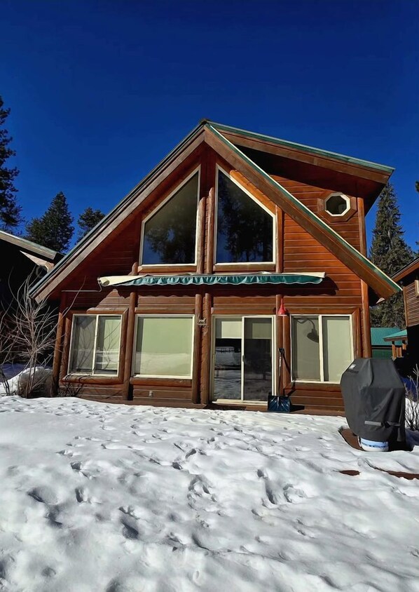 Une cabane en bois dotée de grandes fenêtres et d’une entrée abritée.