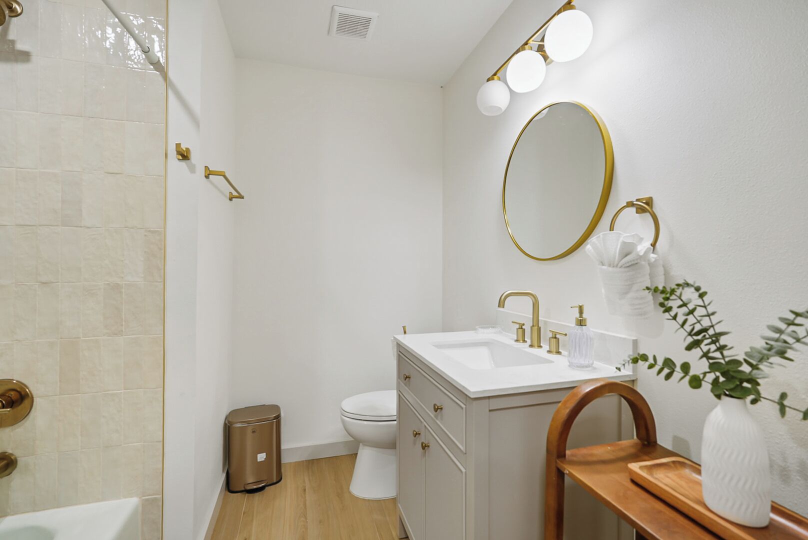 Een badkamer met een witte wastafel, gouden details, een spiegel en een douche.