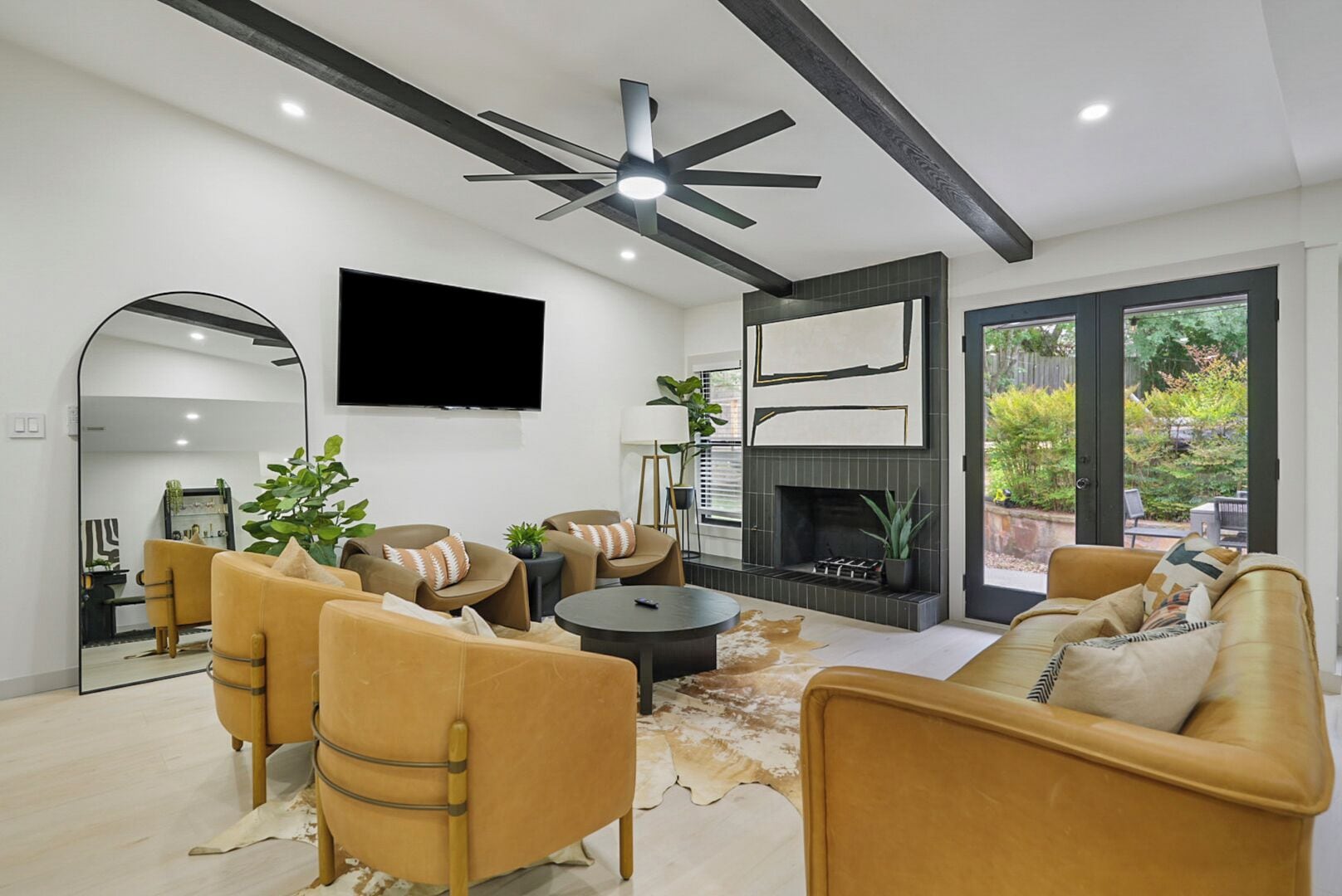 Una sala de estar moderna con chimenea, sofás de cuero, televisor de pantalla plana y ventilador de techo.