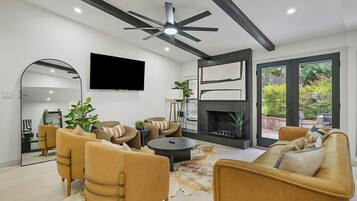 Una sala de estar moderna con chimenea, sofás de cuero, televisor de pantalla plana y ventilador de techo.