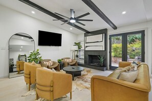 Una sala de estar moderna con chimenea, sofás de cuero, televisor de pantalla plana y ventilador de techo.