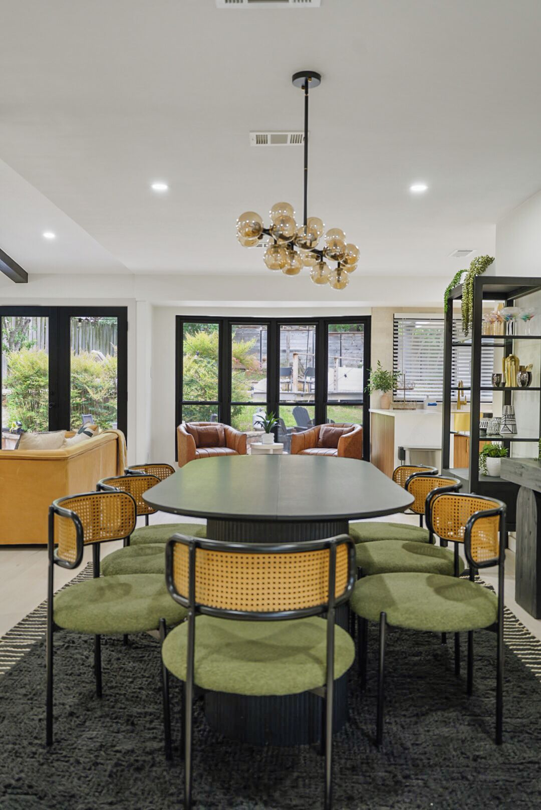 A modern dining area with a round table, six chairs, and a hanging light fixture.