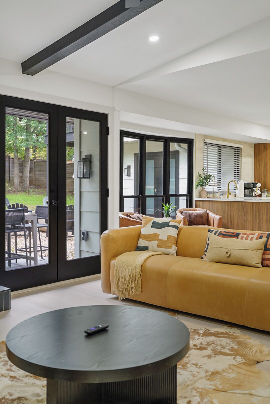 Una sala de estar moderna con un sofá, una mesa de centro y un gran ventanal corredizo que da a un espacio exterior.