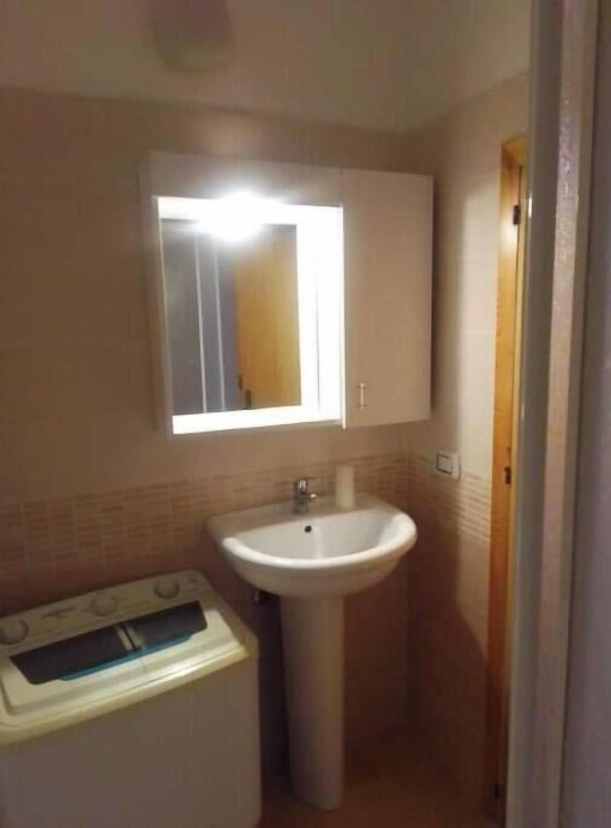 Ein kleines Badezimmer mit einem weißen Waschbecken, einem Spiegel und einer weißen Toilette.