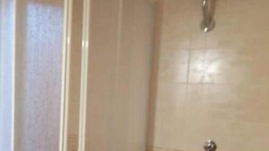 A bathroom with a toilet, a shower area, and a tiled wall. - The Terrace of Campomarino (Campomarino di Maruggio (TA))