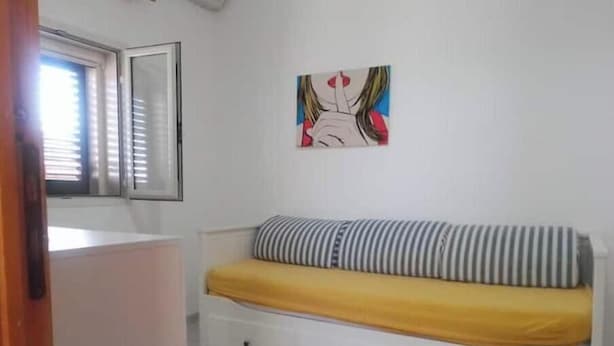 A room with a bed, a window, and a wall-mounted artwork. - The Terrace of Campomarino (Campomarino di Maruggio (TA))