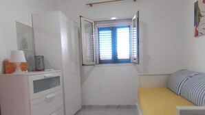 A small room with a bed, a desk, a window with blinds, and a cabinet. - The Terrace of Campomarino (Campomarino di Maruggio (TA))