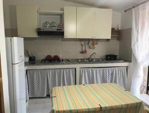 Eine kleine Küche mit Kühlschrank, Herd, Spüle und einem Tisch mit Streifenmuster.