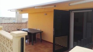 A rooftop terrace with a table and chairs, a sliding door, and a decorative wall. - The Terrace of Campomarino (Campomarino di Maruggio (TA))
