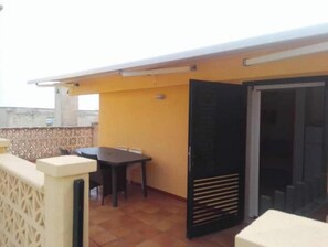 Eine Dachterrasse mit Tisch und Stühlen, einer Schiebetür und einer dekorativen Wand.