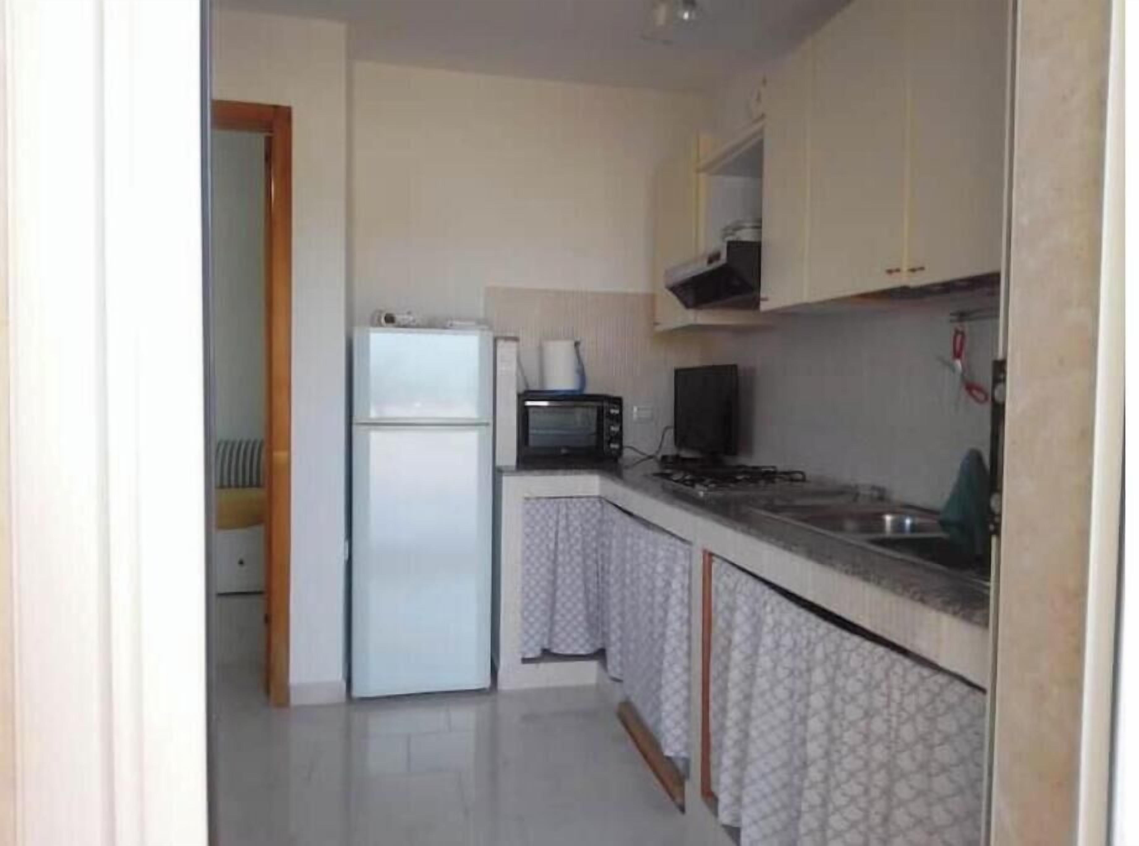 Una cocina funcional con refrigerador, microondas, estufa y lavamanos.