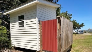Een laag gebouw met een rode deur en een houten trap naar een veranda.