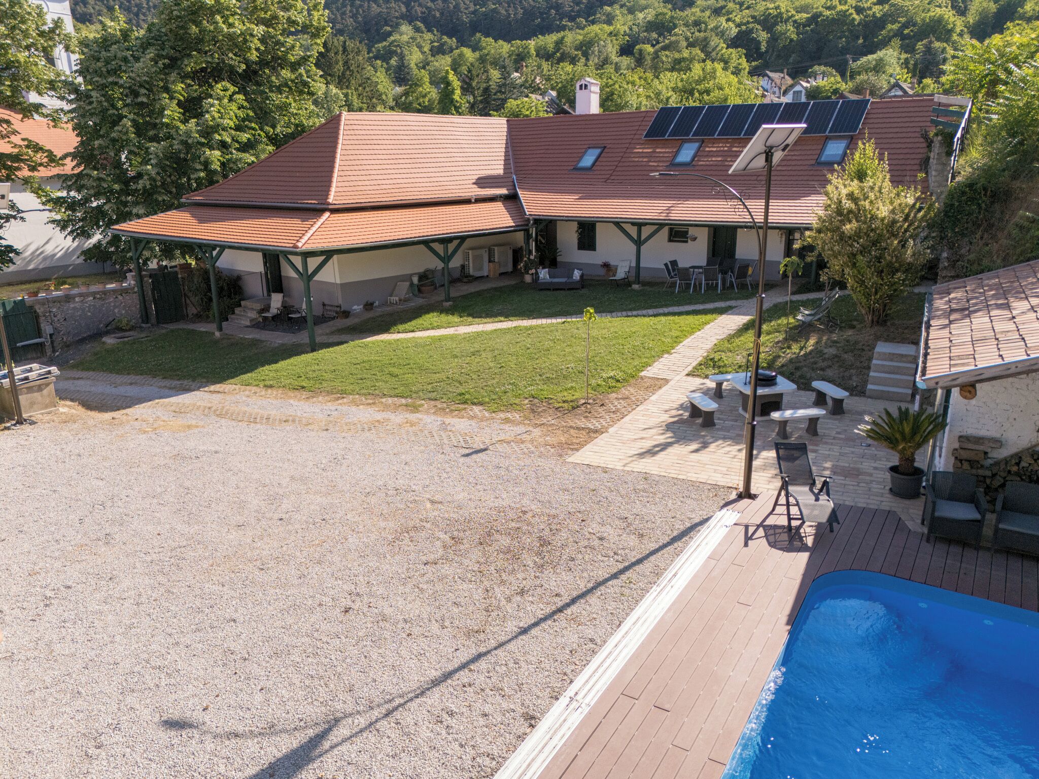A residential property with a swimming pool, solar panels, and a covered patio area.