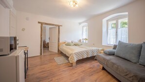 A bedroom with a bed, a sofa, a window, and a door.