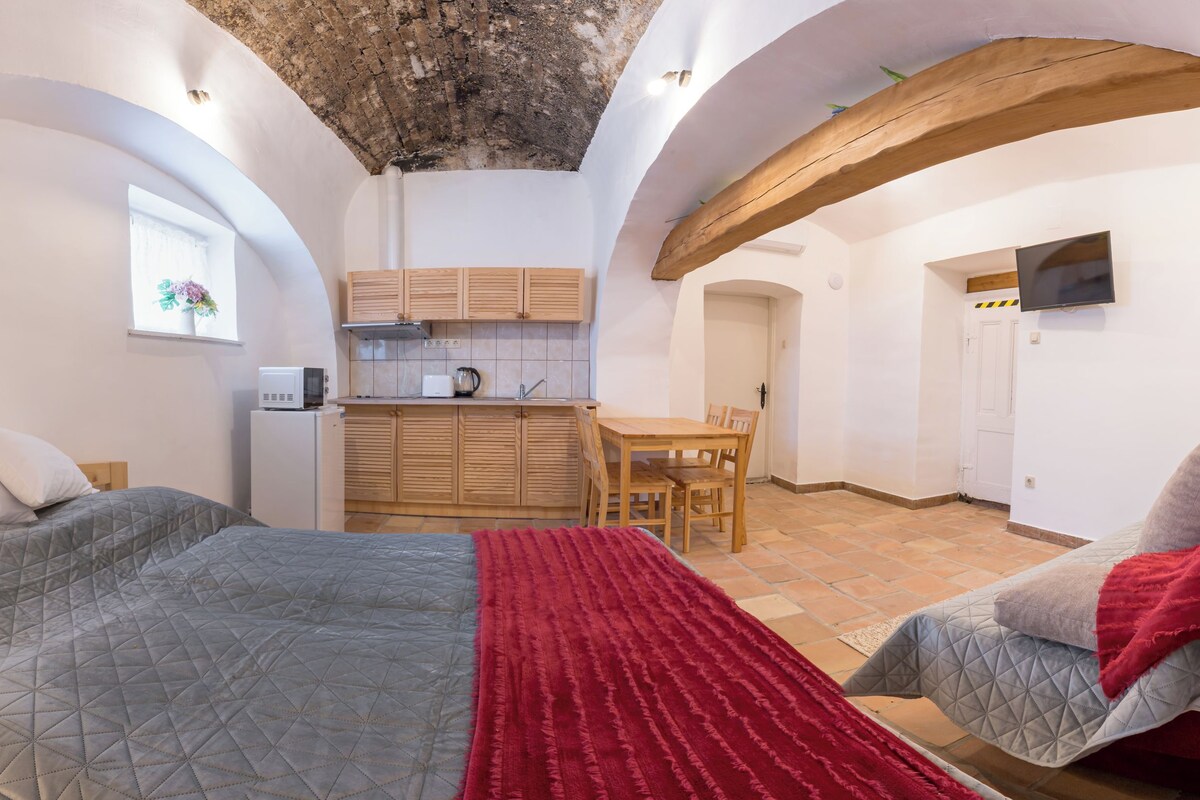 A bedroom with a bed, bedside table, and a red throw blanket.
