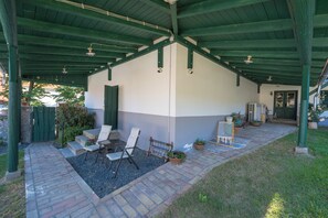 A covered patio area with seating, a door, and a small table.