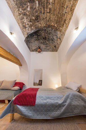 A bedroom with a vaulted ceiling, a bed with a quilted cover, and a red throw blanket. - Döbrögi Wellness Vendégház (Nemesvita)