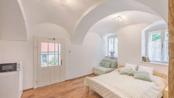A bedroom with a bed, a desk, and a window.