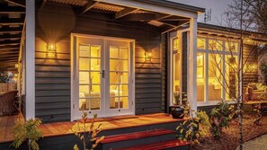 A house with a porch, a set of double doors, and a small garden area with plants.